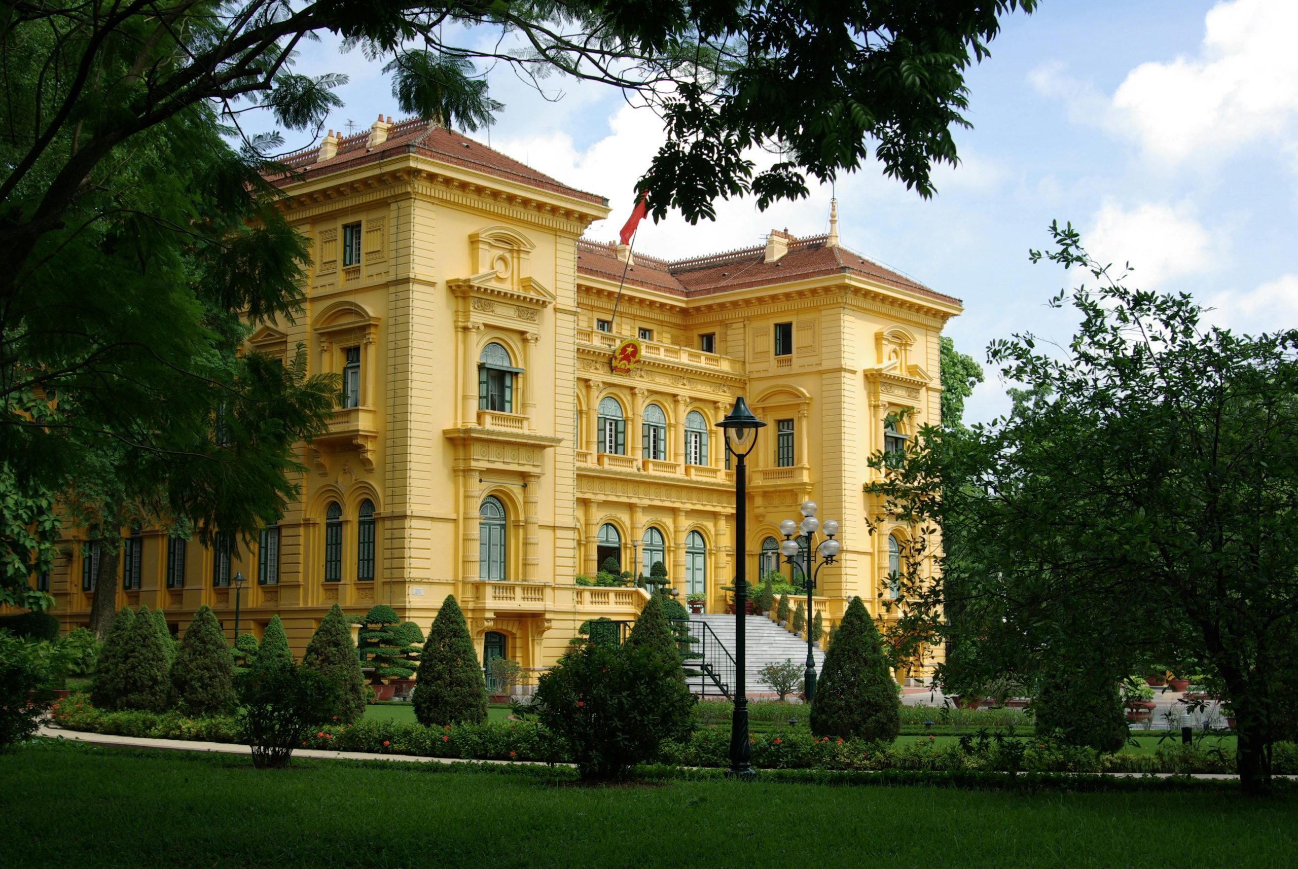 A stunning view of the Presidential Palace in Hanoi surrounded by lush garden greenery.